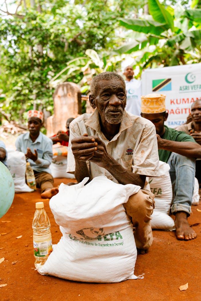 services-03 An elderly man with a food package during a distribution event in a rural setting.